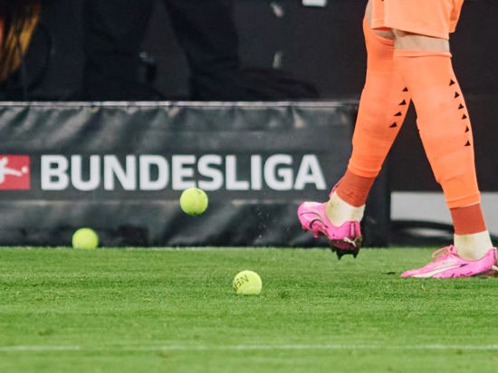 Dortmunds Torwart Gregor Kobel schießt beim Bundesliga-Spiel zwischen Borussia Dortmund und dem SC Freiburg Tennisbälle vom Platz, die Fans aus Protest gegen Investoren in der DFL auf das Spielfeld geworfen haben.