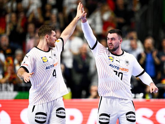 Die deutschen Spieler Johannes Golla (links) und Jannik Kohlbacher klatschen sich bei der Handball-EM im Spiel Deutschland gegen Ungarn in der Kölner Lanxess Arena ab.