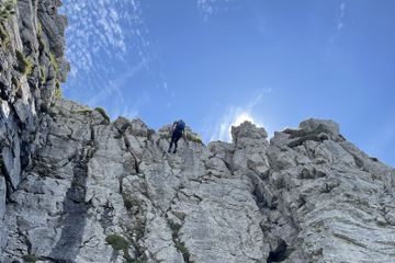Eine Frau lässt sich an einer Steilwand in den Allgäuer Alpen von einem Bergführer abseilen.