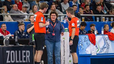 Jutta Ehrmann-Wolf spricht am Rand eines Handballfeldes mit zwei Schiedsrichtern.