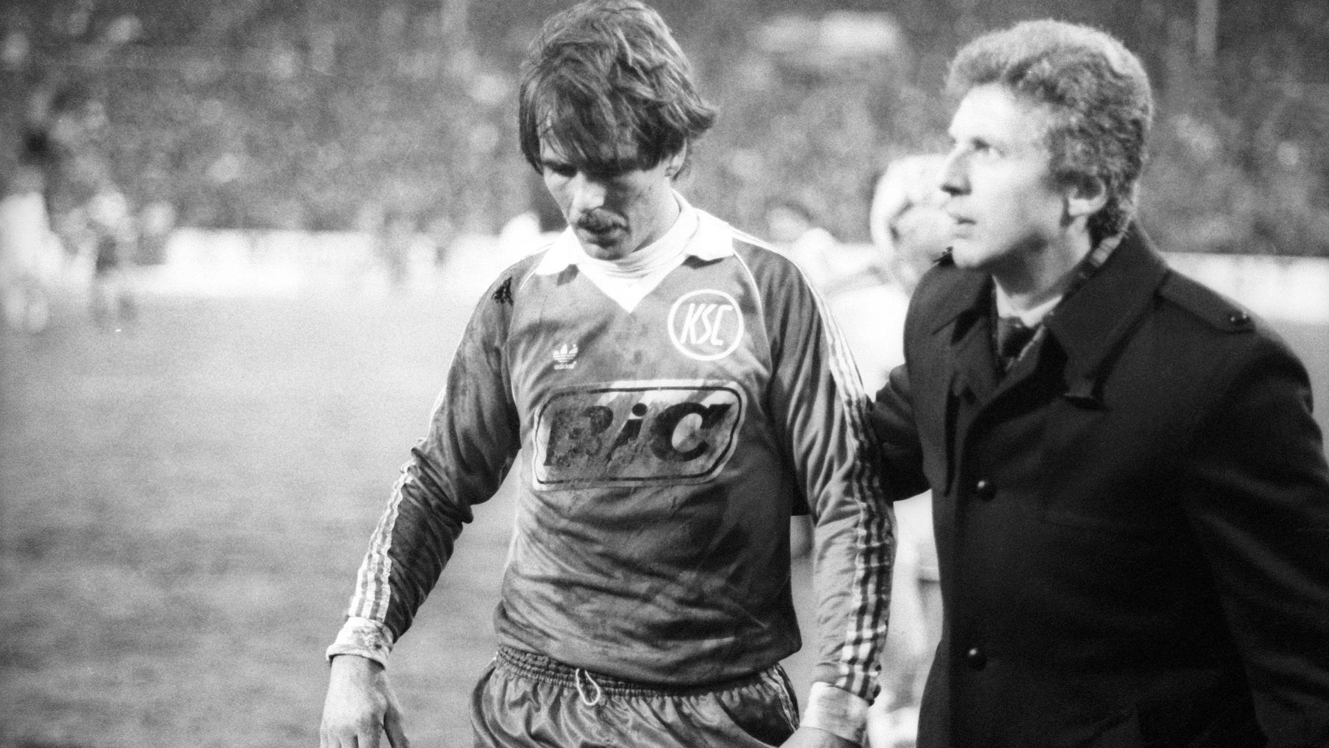 Jacken-Geschäft: Geschäftsführer Manfred Amerell begleitet den in der Saison 1981/1982 beim 1:1 gegen Gladbach vom Platz gestellten KSC-Verteidiger Rolf Dohmen in die Katakomben. 