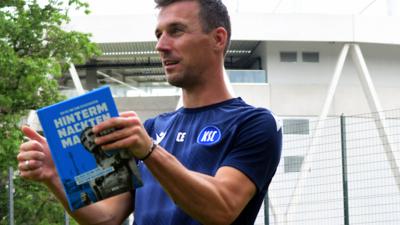 KSC-Trainer Christian Eichner mit einem Exemplar des BNN-Buches „Hinterm Nackten Mann“.