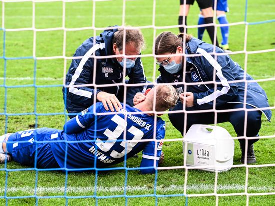 Erstversorgung: Philipp Hofmann wird am Sonntag nach Nicolai Rapps Tritt von KSC-Mannschaftsarzt Marcus Schweizer und der Physiotherapeutin Julia Bohn behandelt