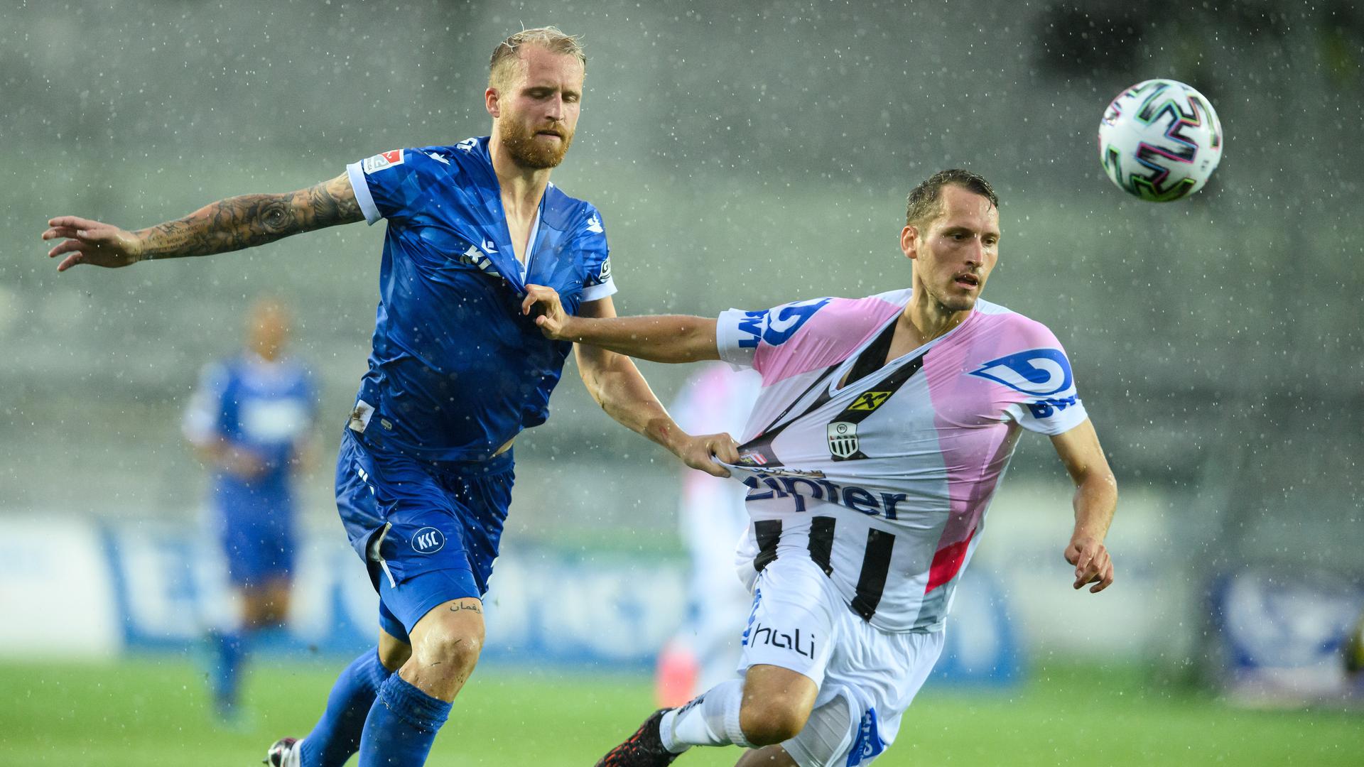 Abnutzungskampf: Im strömenden Regen von Pasching liefert sich der Karlsruher 1:0-Schütze Philipp Hofmann ein Laufduell mit dem Linzer Christian Ramsebner.