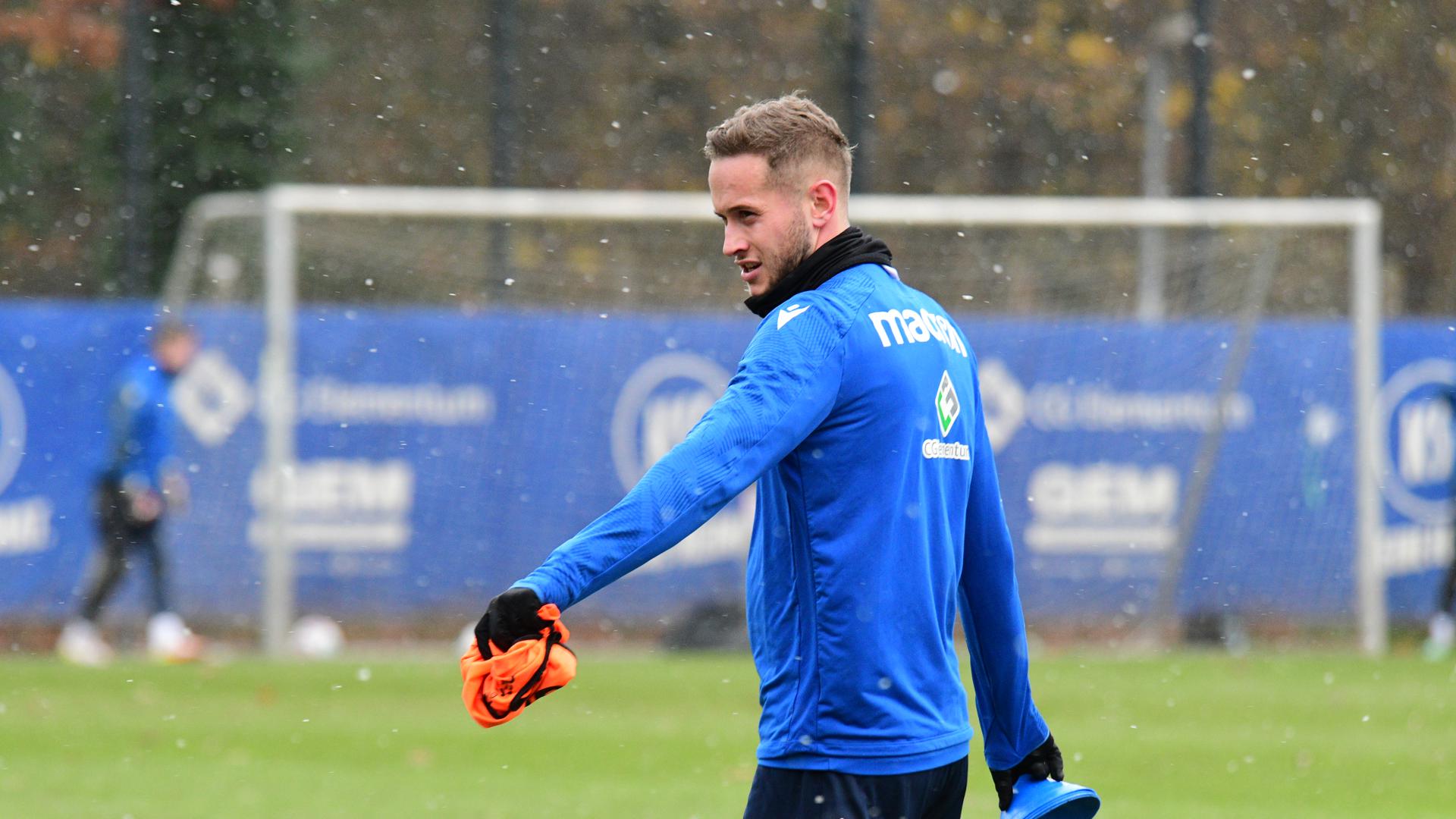 Christoph Kobald trägt Hütchen und ein Hemdchen beim Training des Karlsruher SC, während der erste Schnee vom Himmel fällt.