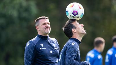 KSC-Trainer Christian Eichner balanciert im Training des Karlsruher SC vor den Augen seines Co-Trainers Zlatan Bajramovic einen Ball auf dem Kopf.