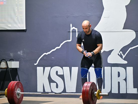 Gewichtheber Kevin Schweizer steht auf der Bühne und fokussiert die Hantel.  