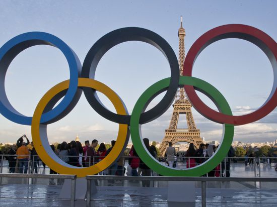 Die Olympischen Ringe stehen vor dem Eiffelturm.