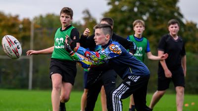 Das Rugby-Ei im Blick: Nachwuchsspieler des Karlsruher SV beim Training, in dem gemischte Altersklassen gemeinsam auf dem Rasen stehen.
