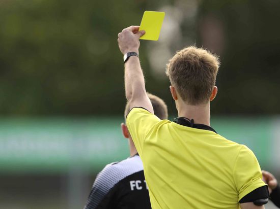 Ein Schiedsrichter zeigt die Gelbe Karte 