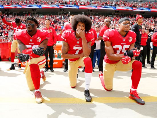 Colin Kaepernick (M), Eli Harold (l) und Eric Reid von den San Francisco 49ers knien 2016 beim Abspielen der US-Nationalhymne.