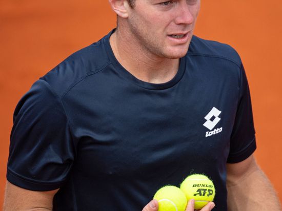 Dominik Koepfer hält zwei Tennisbälle in der Hand.