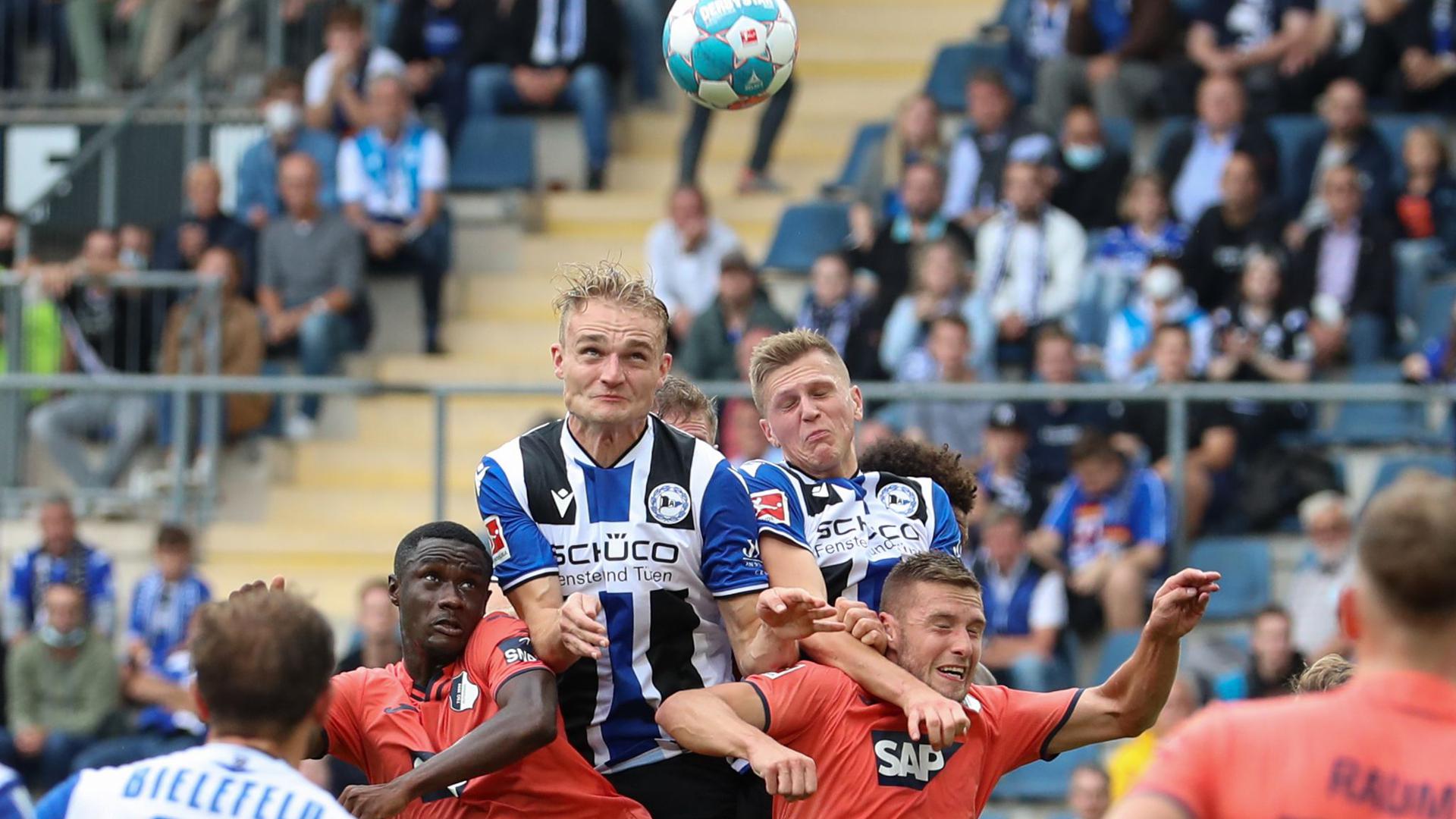 Bielefelds Amos Pieper (oben, l) setzt sich im Kopfballduell gegen Hoffenheims Diadie Samassekou (unten, l-r) und Pavel Kaderabek durch.