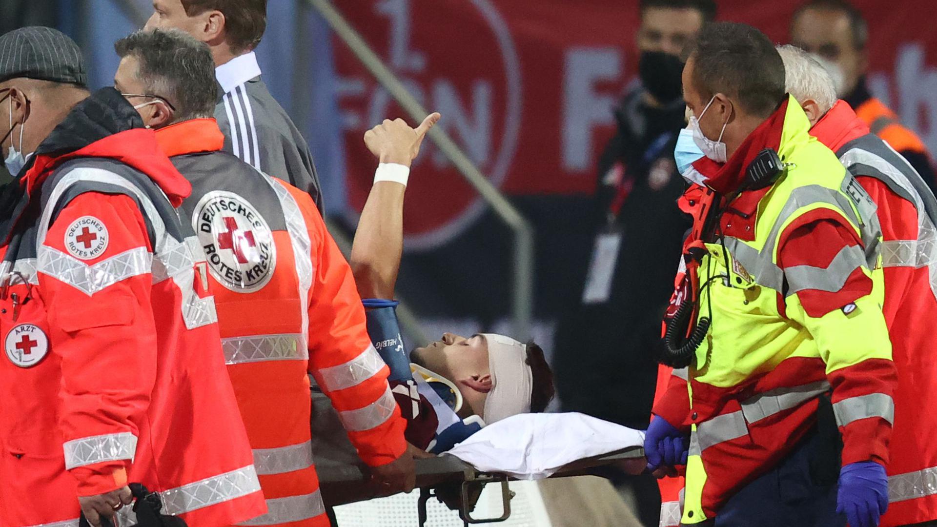 Der Nürnberger Tom Krauß (M) wird verletzt aus dem Stadion getragen, zeigt aber mit dem Daumen nach oben.