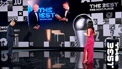 Dem FCB-Stürmer Robert Lewandowski (r. auf Bildschirm) wird 2020 die Weltfußballer-Trophäe überreicht.