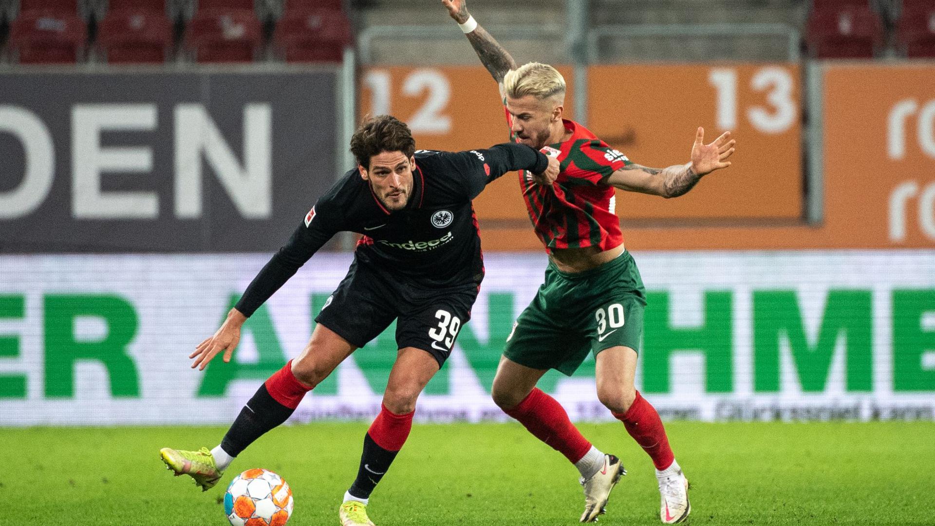 Goncalo Paciencia von Eintracht Frankfurt (l) schirmt den Ball gegen Augsburgs Niklas Dorsch ab.