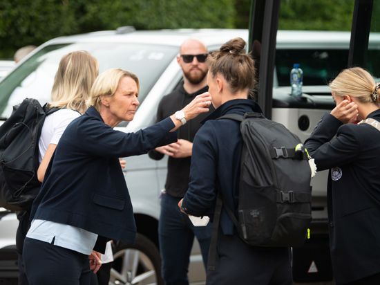 Bundestrainerin Martina Voss-Tecklenburg (l) versucht Spielerinnen bei der Abreise aufzumuntern.