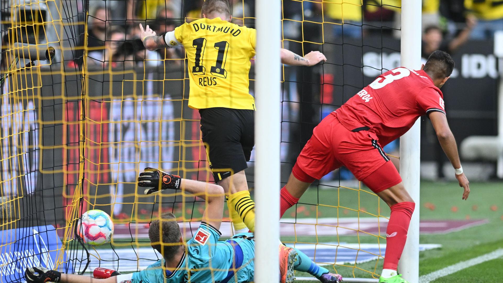 Dortmunds Marco Reus (M) stochert den Ball gegen Leverkusens Torwart Lukas Hradecky (l) und Piero Hincapie über die Linie.